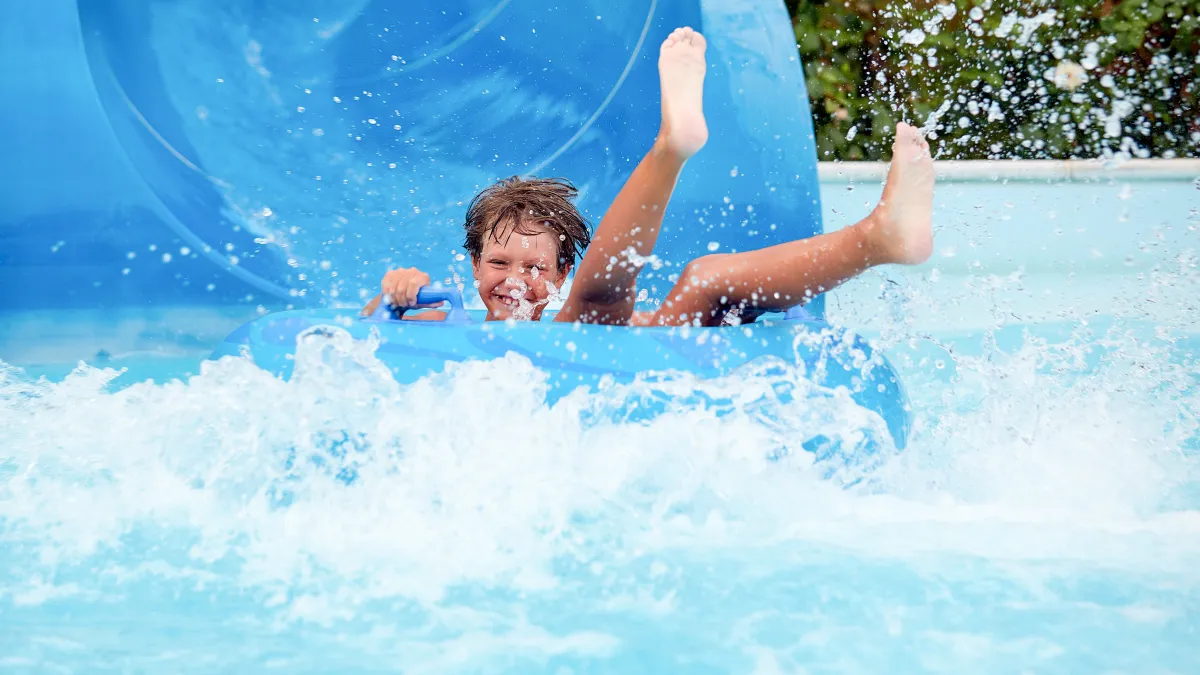 Young boy laughing on an inflatable circle going down a waterslide