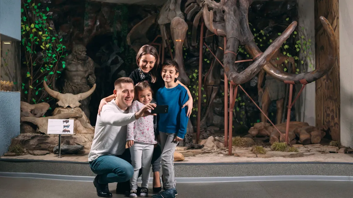 Family taking a photo with a dinosaur museum exhibit