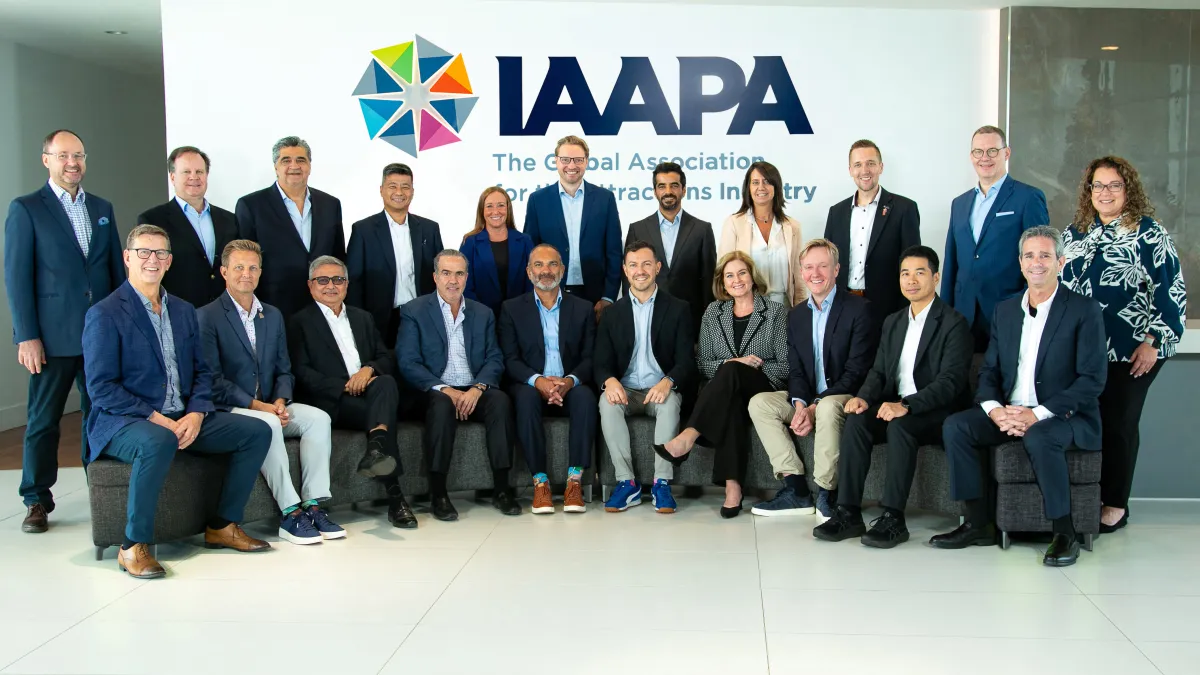 25 people from the IAAPA Board standing in lobby looking at camera. 