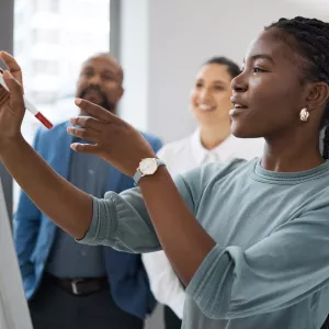 Black Female professional working on a whiteboard
