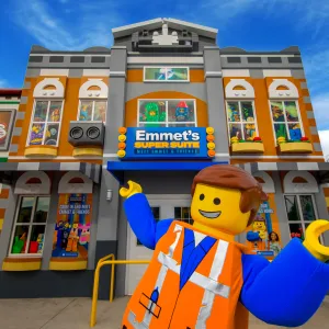 Emmet stands in front of Emmet's Super Suite at LEGOLAND California's LEGO Movie World, showcasing a vibrant LEGO landscape.
