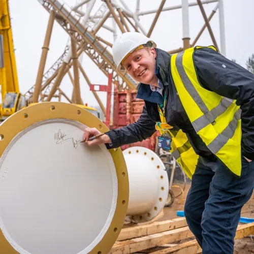 Dan Warwick putting his signature on a support column of a rollercoaster waiting to be constructed.