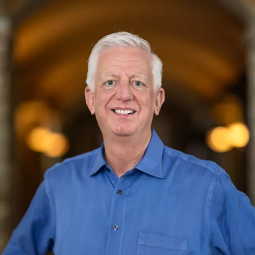 Man smiling wearing a blue collared button down top