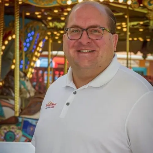 Man wearing white collared shirt in front of amusement ride