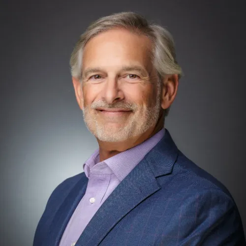 RAC smiling at the camera wearing a dark blue suit