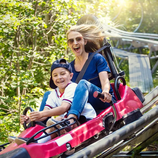 Woman and child riding downhill together on an alpine slide