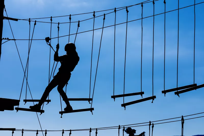Silhouette of young girl on high rope course