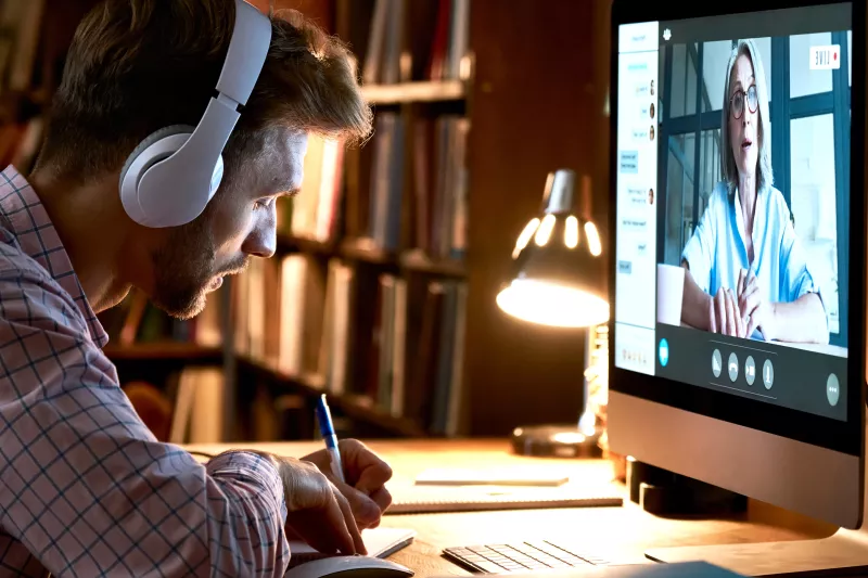 Male student wearing headphones watching webinar