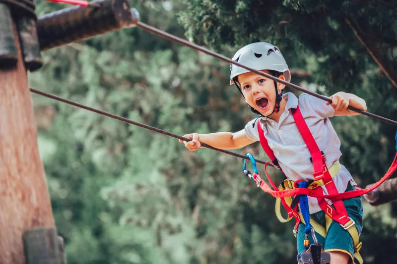 Little boy climbing in adventure activity park