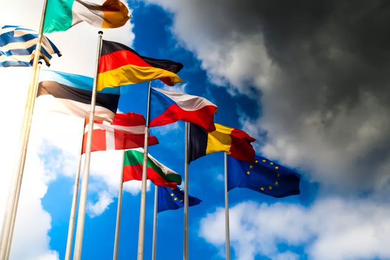 European Flags waving in the wind against a blue sky