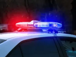 Police Car with swirling red and blue lights on while on an active crime scene
