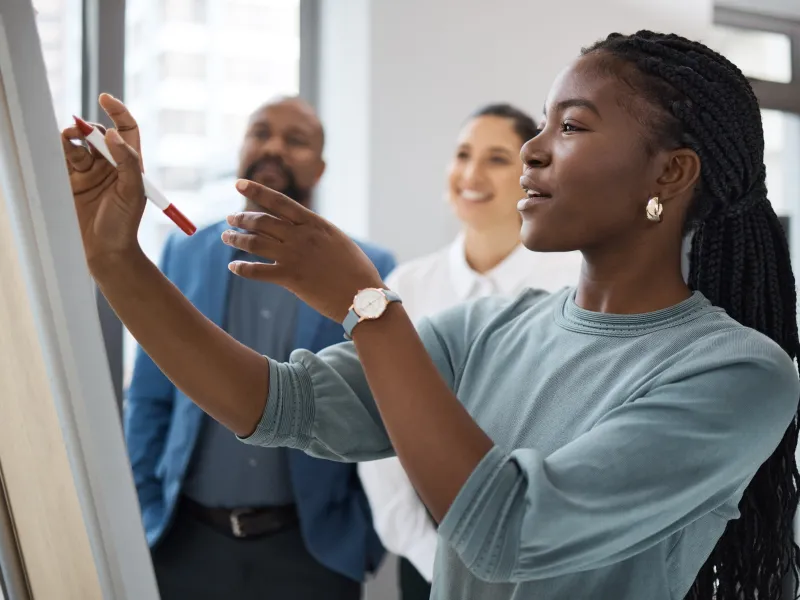 Black Female professional working on a whiteboard