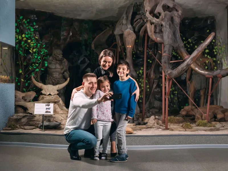 Family taking a photo with a dinosaur museum exhibit 