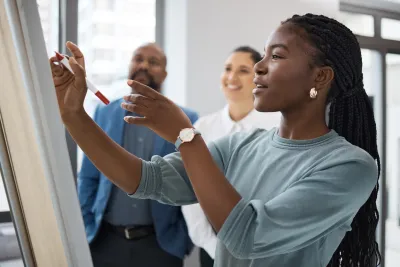 Black Female professional working on a whiteboard