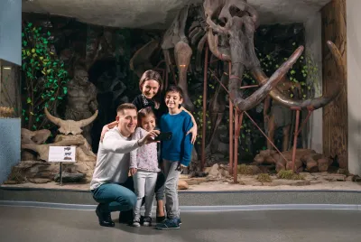 Family taking a photo with a dinosaur museum exhibit 