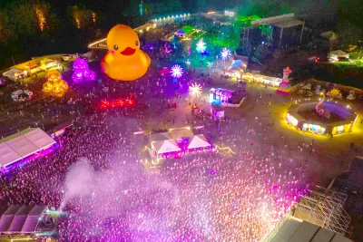 A giant inflatable duck sits behind a concert stage at night creating a festival atmosphere. 