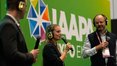 Speakers holding a microphone on stage at IAAPA Expo Europe 