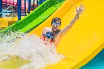 Man with child slide down water slide