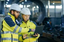 Male & Female Engineers discuss new project on a laptop in a warehouse