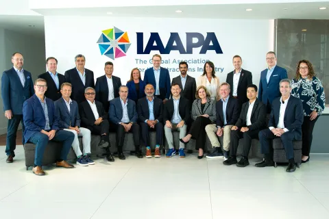 25 people from the IAAPA Board standing in lobby looking at camera. 