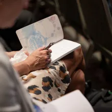 Person holding a pen and notebook to take notes